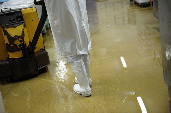 Travailleur portant des bottes antidérapantes se déplaçant sur un sol humide dans une entreprise agroalimentaire Travailleur portant des bottes antidérapantes se déplaçant sur un sol humide dans une entreprise agroalimentaire