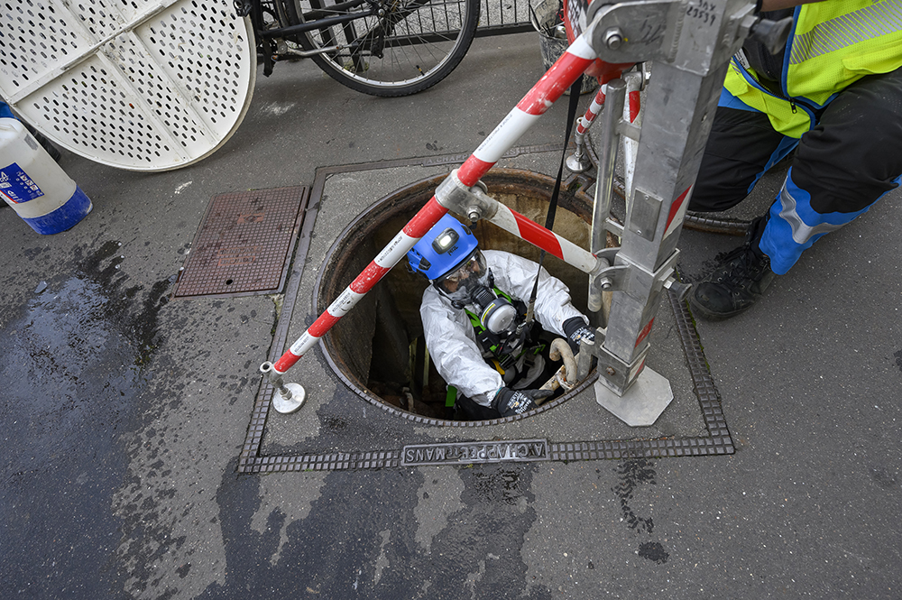 Un salarié descend équipé dans une bouche d'égout. Un salarié descend équipé dans une bouche d'égout.